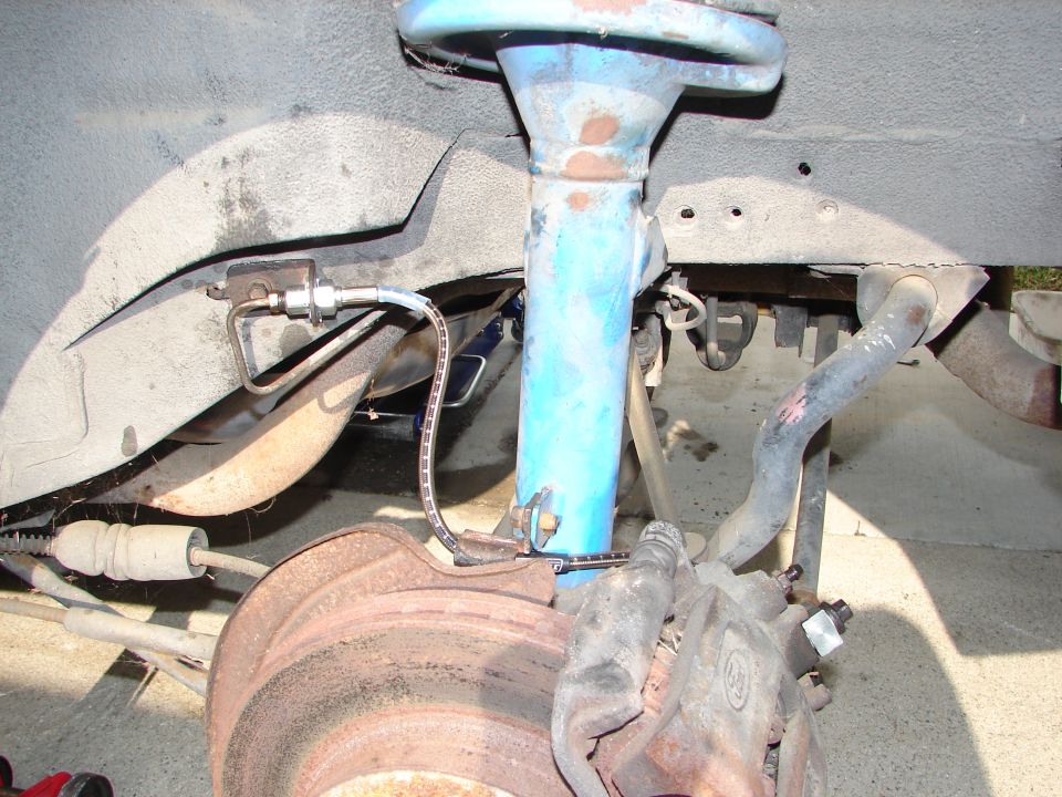 close-up of a car's front brake rotor, caliper, and suspension strut