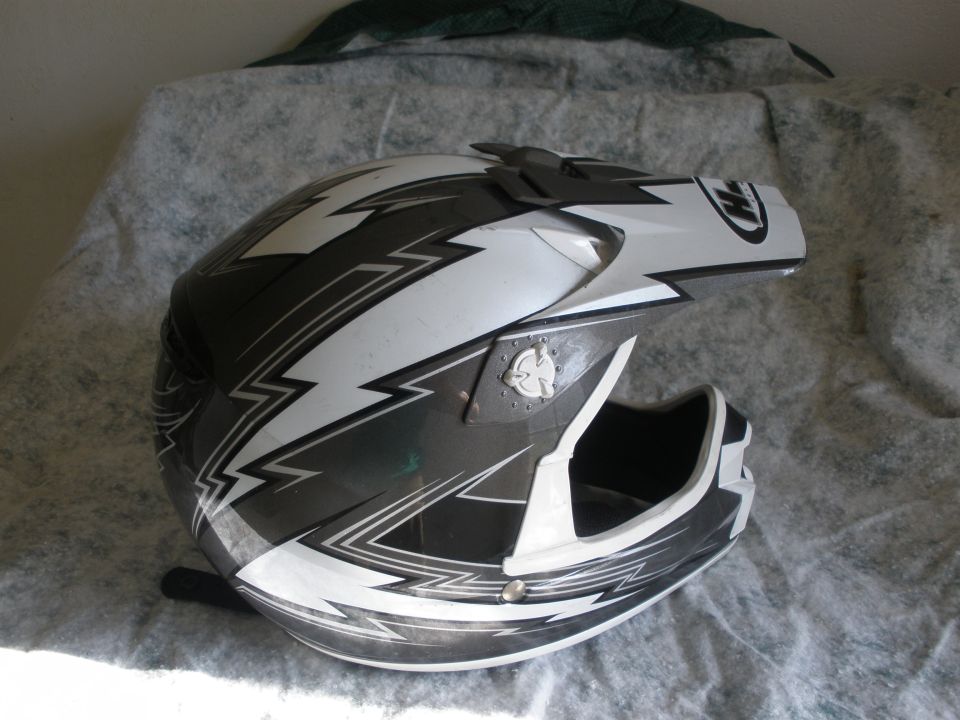 Black and white graphic motorcycle helmet on a textured surface. Supermotors.net logo in lower right corner