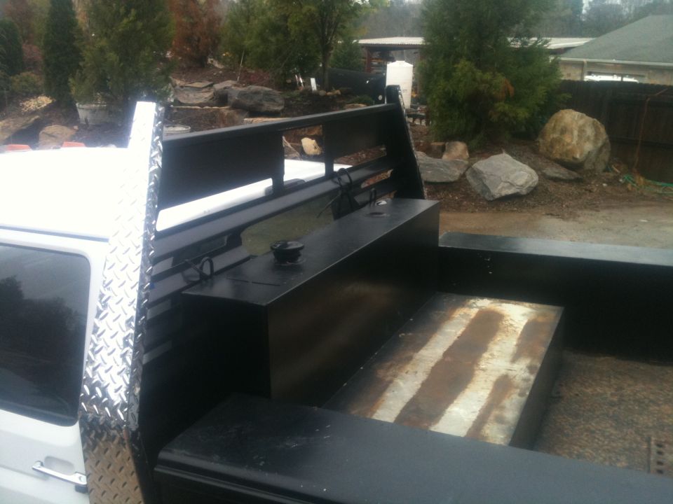 1997 Ford F-350 truck bed with diamond plate trim, black fuel tank, and rusty metal floor