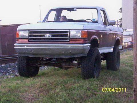 1989 Ford Bronco - This lifted 1987 Ford F-Series truck features a prominent front grille and two-tone paint scheme.