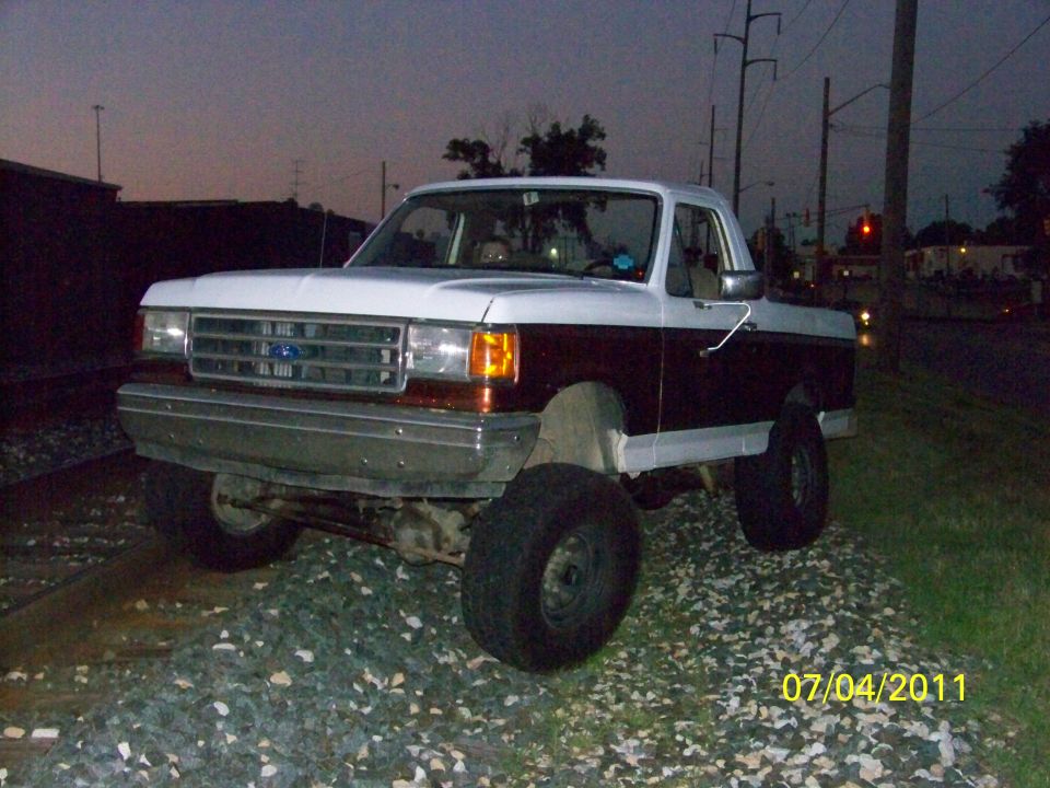 1989 Ford Bronco parked on train tracks at dusk