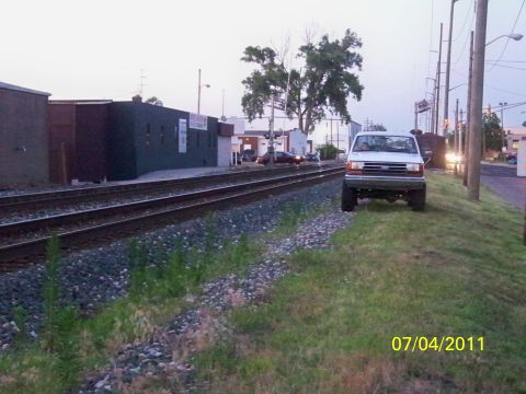 1989 Ford Bronco - A white Ford F-Series truck is parked on a grassy area next to railroad tracks at dusk.
