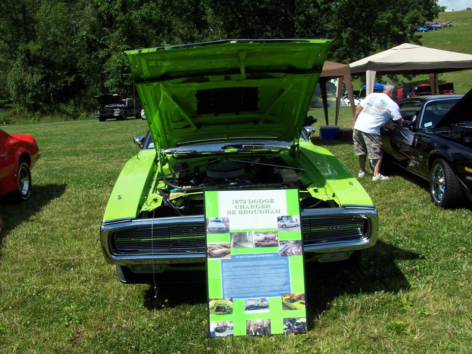 Lime green 1973 Dodge Charger SE Brougham, hood up, with show display board at car show