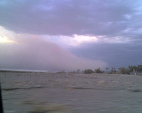 2009 Kenworth T800 - A large dust storm is visible in the distance, moving across a barren landscape under a dramatic sky.