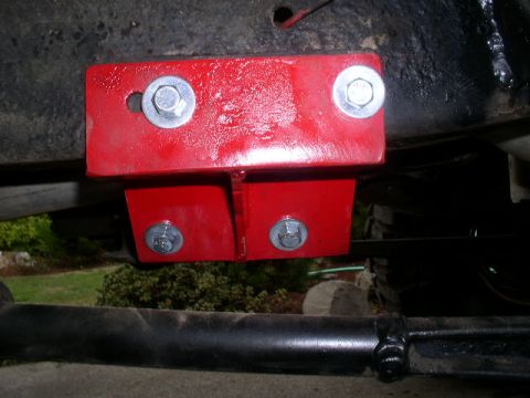 1979 Ford Bronco - Close-up view of a red painted metal bracket attached to the underside of a vehicle.
