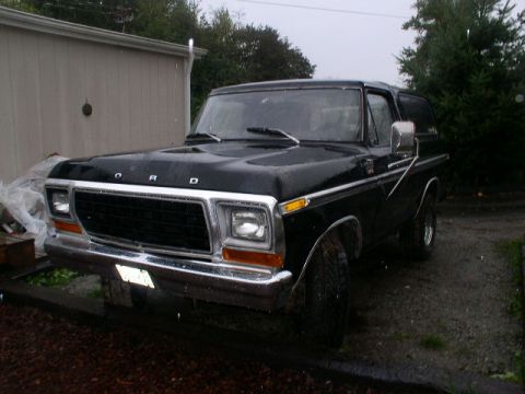 1978 Ford Bronco - A black 1970s-era Ford Bronco full-size SUV photographed from the front three-quarter angle, showing chrome grille with 'FORD' lettering, a…