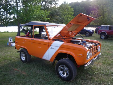 1995 Ford Bronco - First-generation Ford Bronco parked outdoors with its hood open, other vehicles in the background.