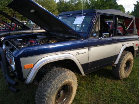 1995 Ford Bronco - Ford Bronco on display with hood open, parked on grass at an outdoor event.