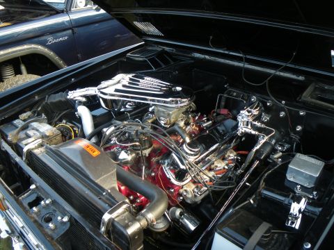 1995 Ford Bronco - The engine bay of a classic vehicle is shown, with a second Bronco in the background.