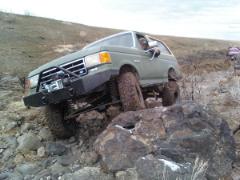 1989 Ford Bronco - This modified green Ford Bronco tackles a challenging rocky trail, its off-road capabilities.