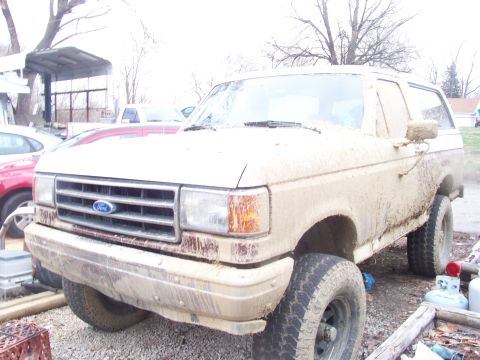 1989 Ford Bronco - This heavily mud-splattered 1987 Ford Bronco is viewed from the front three-quarter angle.