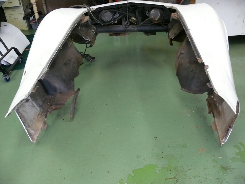White car front clip with exposed engine components and damaged fender liners