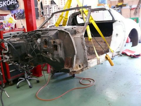 1976 Chevrolet Corvette - This vehicle's body is suspended by yellow straps, revealing its stripped-down frame and interior during a repair process.