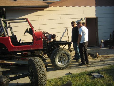 1990 Jeep YJ - A red Jeep YJ is seen partially disassembled in a driveway, with several people observing the work.