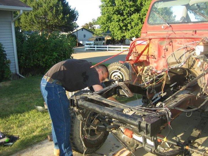 Red Jeep YJ chassis, front view, with person working on engine bay