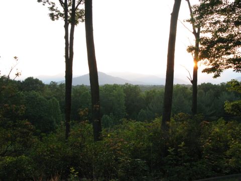 1971 Ford Ranchero - A hazy sunset over a vast forest and distant mountains, framed by trees.