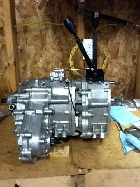 1988 Suzuki Samurai - A silver transfer case with dual shifters is shown on a workbench, with a "Supermotors.net" logo visible at the bottom.