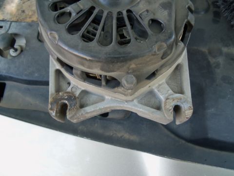 2000 Mercury Grand Marquis - Close-up view of an alternator and its mounting bracket, showing the U-shaped slots for attachment.