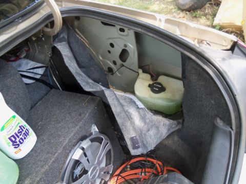 2000 Mercury Grand Marquis - The interior of a car trunk shows a subwoofer, cleaning supplies, and a fluid reservoir.