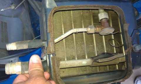 1991 Ford Festiva - A hand holds a hose connected to a vehicle's heater core assembly.