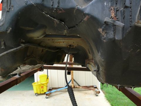 1976 Chevrolet Corvette - Underside of a car frame, showing significant rust and damage, supported by a metal stand.
