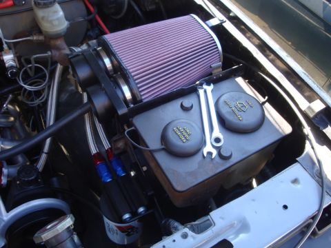 1989 Ford Bronco - Close-up of an engine bay an aftermarket air intake system and a coolant reservoir with service instructions.