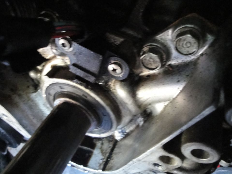 Close-up of an engine component with a black sensor attached by two screws