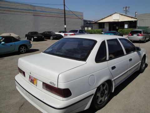 1993 Ford Taurus - White 1993 Ford Taurus sedan seen from the rear quarter angle in a parking lot.