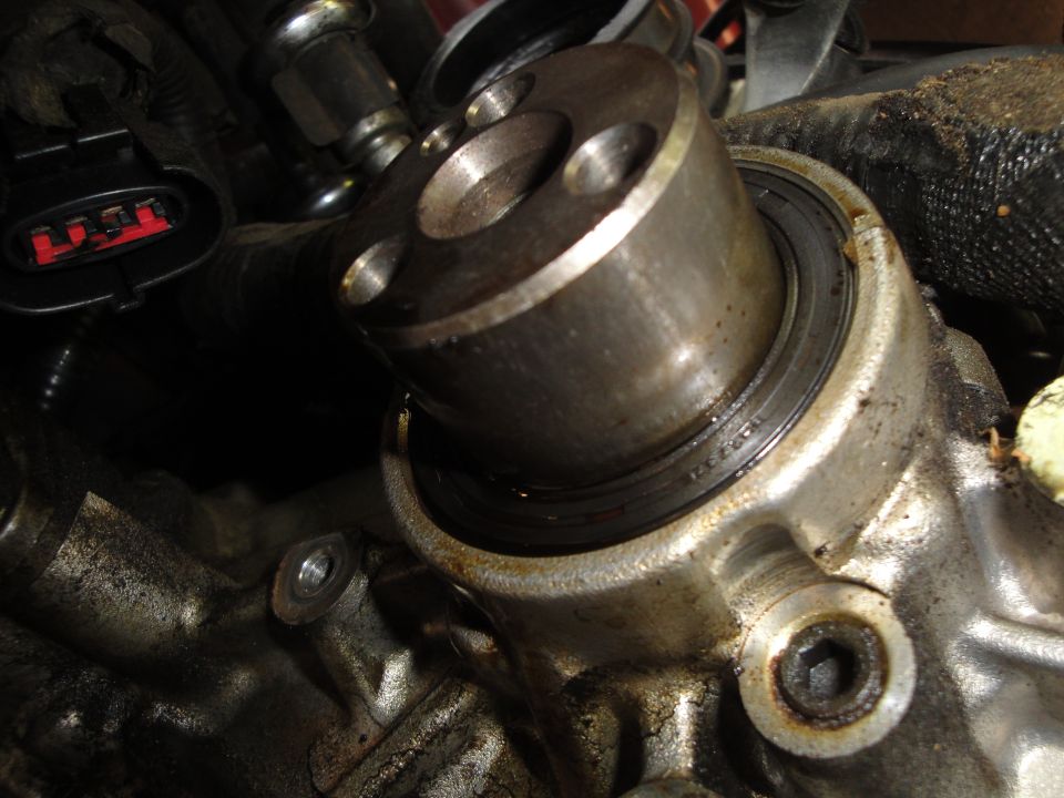 close-up of a greasy engine component with a metal cylinder and bolts