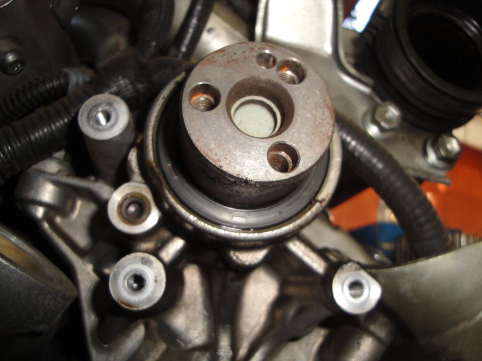 Close-up of a metal engine component with bolts and a rubber seal