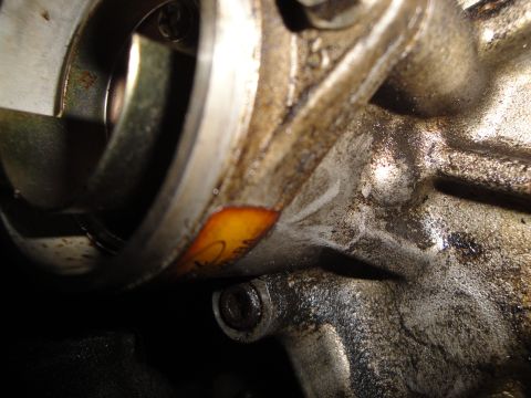 1993 Ford Taurus - Greasy engine part with an orange sticker that has some writing on it.