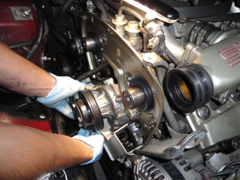 1993 Ford Taurus - Mechanic's hands are visible as they work on the engine, focusing on a pulley system.