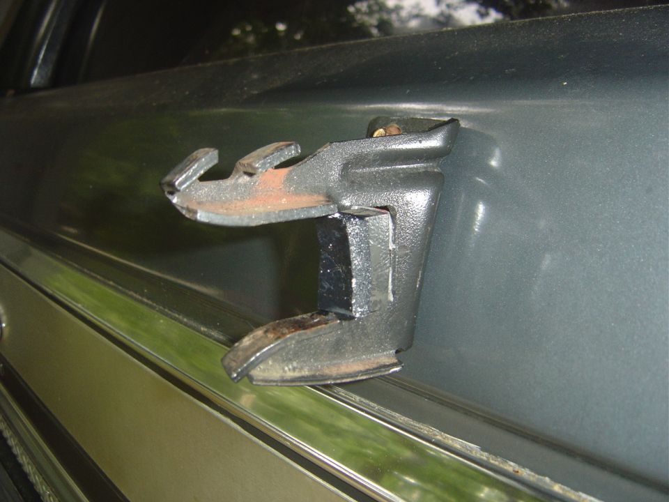 Close-up of a rusty spare tire carrier latch mechanism on a vehicle