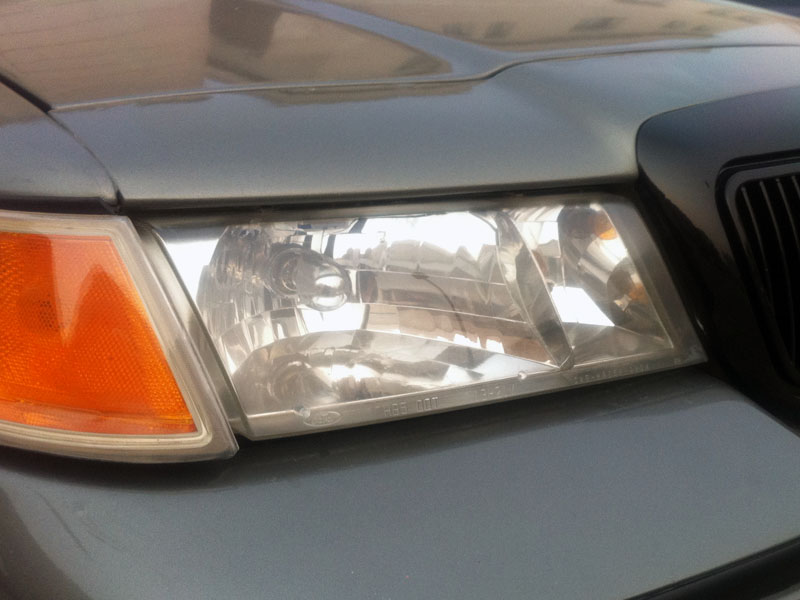 Front corner of a 2001 Mercury Grand Marquis showing the headlight and part of the grille