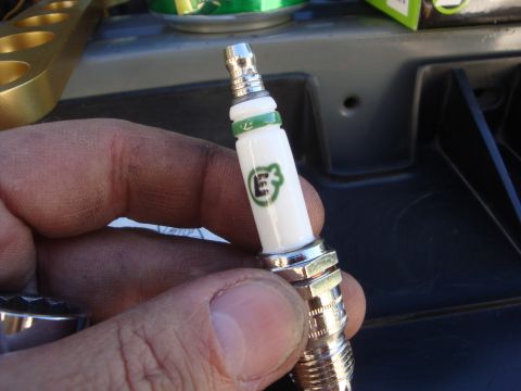 1989 Ford Bronco - A hand holds a spark plug with the E3 logo, likely for a vehicle maintenance task.