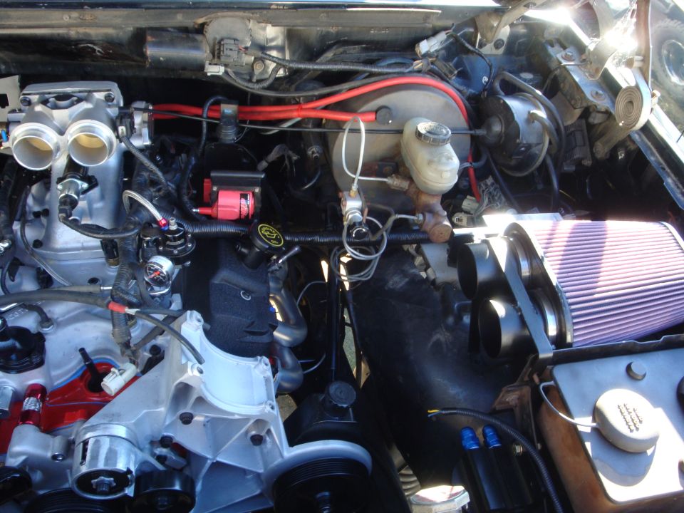 Engine bay with dual throttle bodies, red wiring, and a large air filter