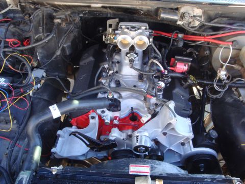 1989 Ford Bronco - Engine bay a V8 engine with dual throttle bodies and prominent red accents on the valve covers.