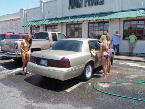 2000 Mercury Grand Marquis - Women in bikinis wash a gold sedan and a pickup truck outside a Twin Peaks restaurant.