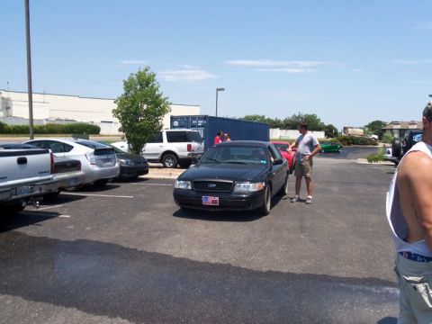 2000 Mercury Grand Marquis - A black 2000 Mercury Grand Marquis is parked in a lot, with a man standing next to it.