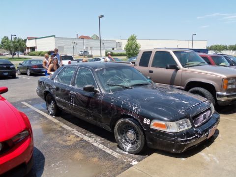 2000 Mercury Grand Marquis - A black sedan, possibly a 2000 Mercury Grand Marquis, is covered in soap suds at a car wash.