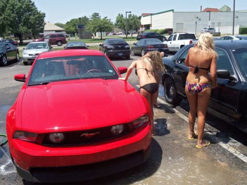 2000 Mercury Grand Marquis - A red Ford Mustang is being washed by two women in bikinis at an outdoor car wash.