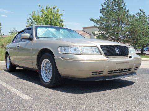 2000 Mercury Grand Marquis - A gold 2000 Mercury Grand Marquis is parked in a lot on a sunny day.