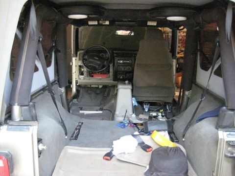 2005 Jeep Wrangler - Interior of a Jeep Wrangler shot from the open tailgate during a stereo/interior teardown: the rear bench and passenger seat are out, the d…