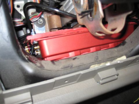 2005 Jeep Wrangler - View up under the dash of a vehicle with the lower trim panel removed, showing a red car-audio amplifier tucked above the pedal area with g…
