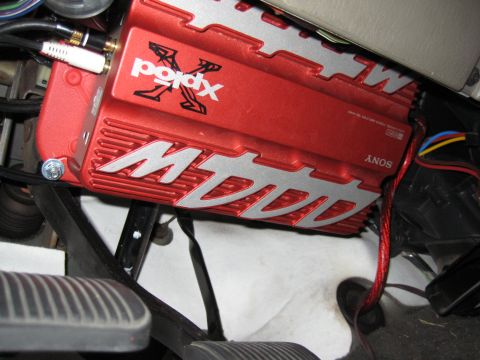 2005 Jeep Wrangler - A red Sony Xplod XM-series car audio amplifier mounted upside down under the dash above the brake and accelerator pedals, with silver heat-…