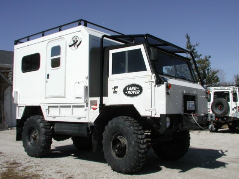 1991 Ford LTD Crown Victoria - A white expedition camper truck is parked outside under a clear blue sky, with another similar vehicle visible in the background.