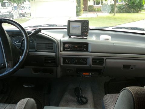 1988 Ford Bronco - The interior of a truck shows a dashboard equipped with a GPS unit, radio, and CB radio, along with the steering wheel.