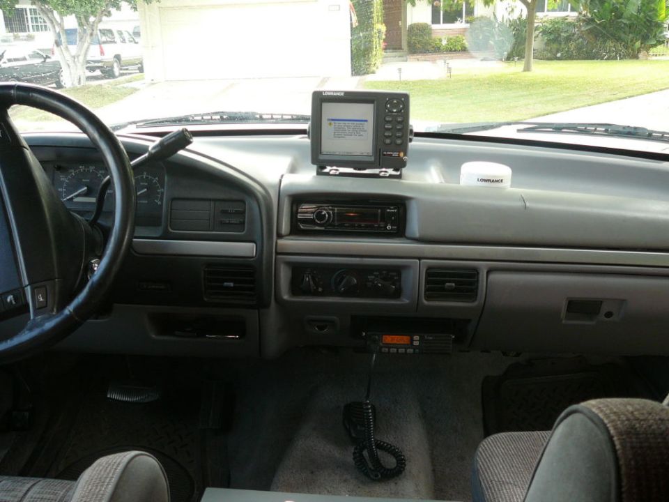 Dashboard of a truck with a steering wheel, radio, GPS unit, and CB radio