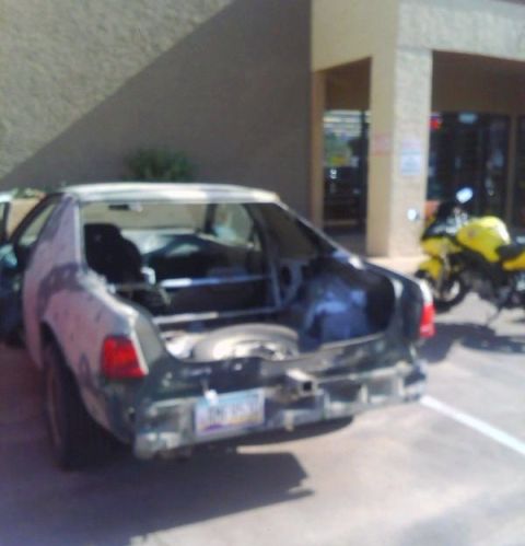2006 Ford E350 - A car with its trunk open and rear bumper removed is parked next to a yellow motorcycle.