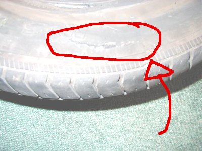 1997 Ford Taurus - Close-up of a damaged tire with a section circled in red, indicating a popped or blown-out area. The Supermotors.net logo is visible at the…